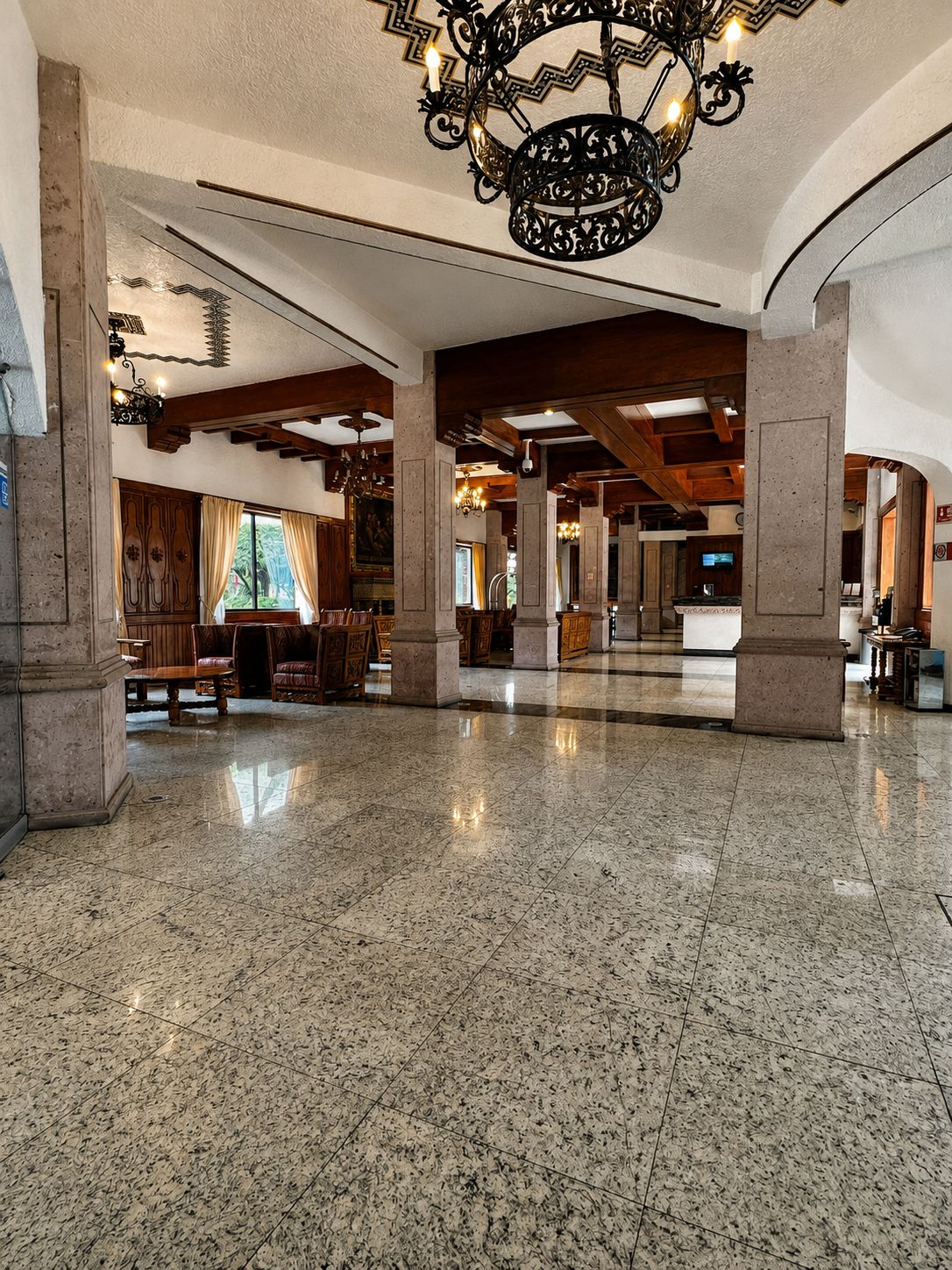 Un vestíbulo amplio con techo alto, candelabros ornamentales y un piso de mármol pulido.
