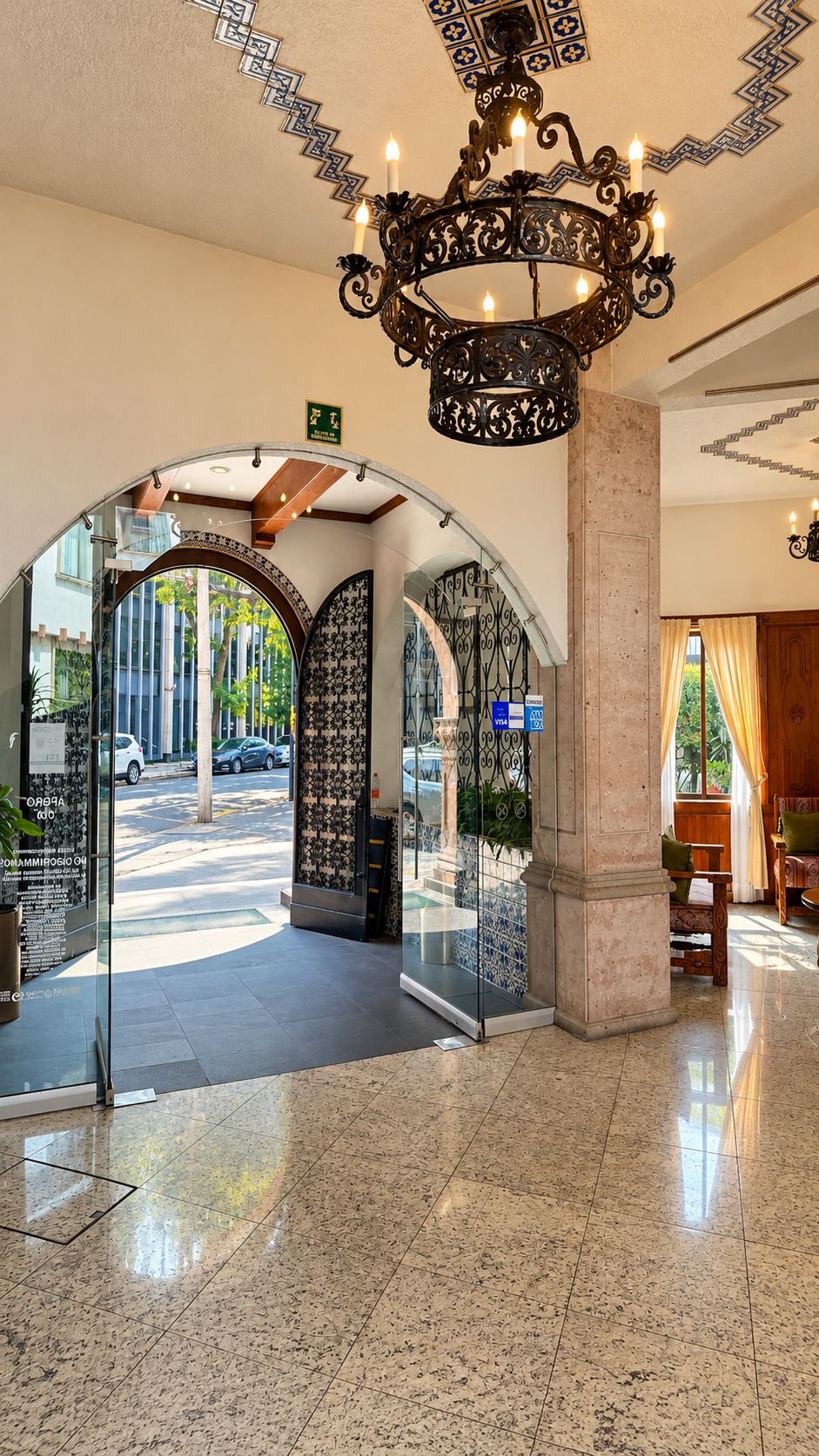 Un hall con candelabro, entrada de cristal y vista a la calle.