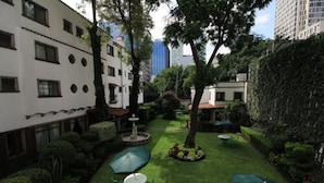 A courtyard with neatly trimmed grass, a fountain, and outdoor seating areas.