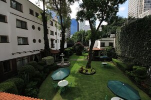 Un patio con césped cuidado, una fuente y zonas de estar al aire libre.