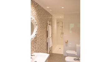A bathroom with a mosaic wall, a white sink, a toilet, and a shower area.