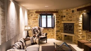 A cozy living room with a stone wall, a fireplace, a sofa, and a coffee table.