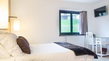 Een slaapkamer met een bed, een bureau, een stoel, een raam en een radiator.