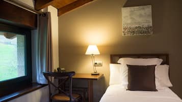 Una habitación de hotel con una cama, un escritorio con lámpara, una silla y una ventana con cortinas.