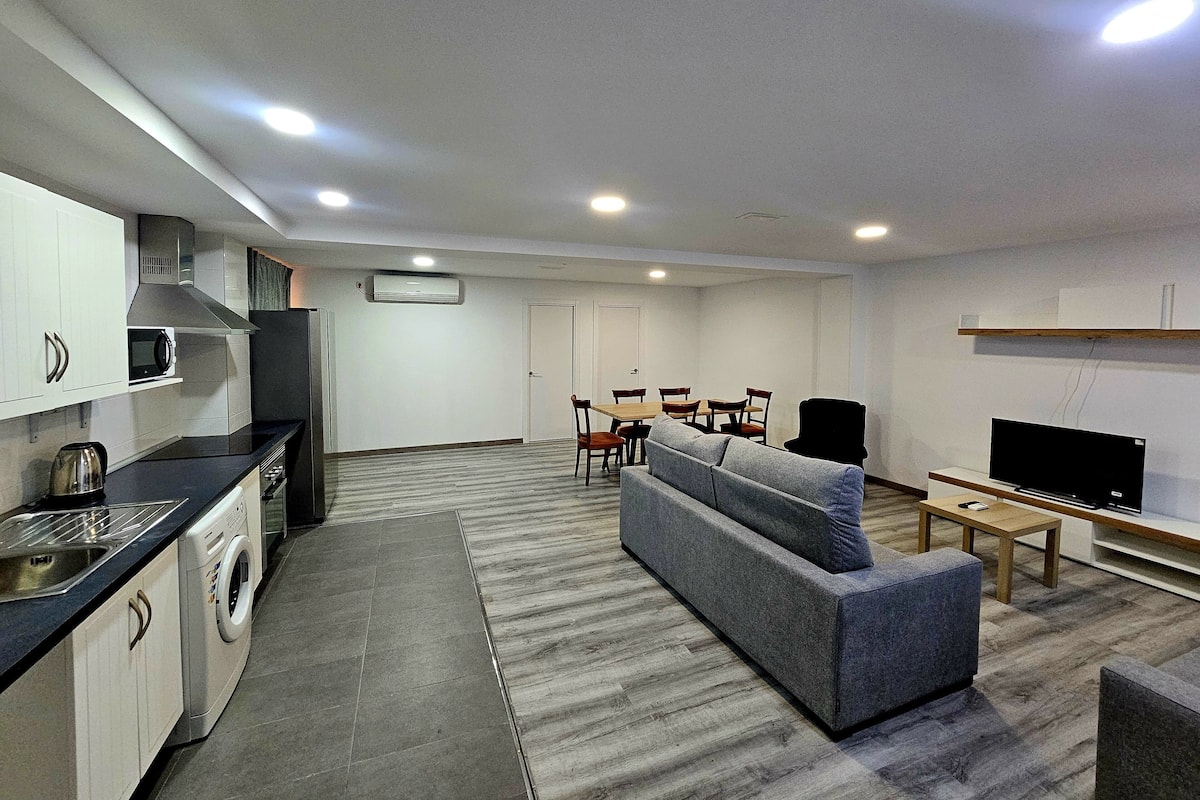 A compact living space with a kitchenette, a sofa, a TV, and a dining area.