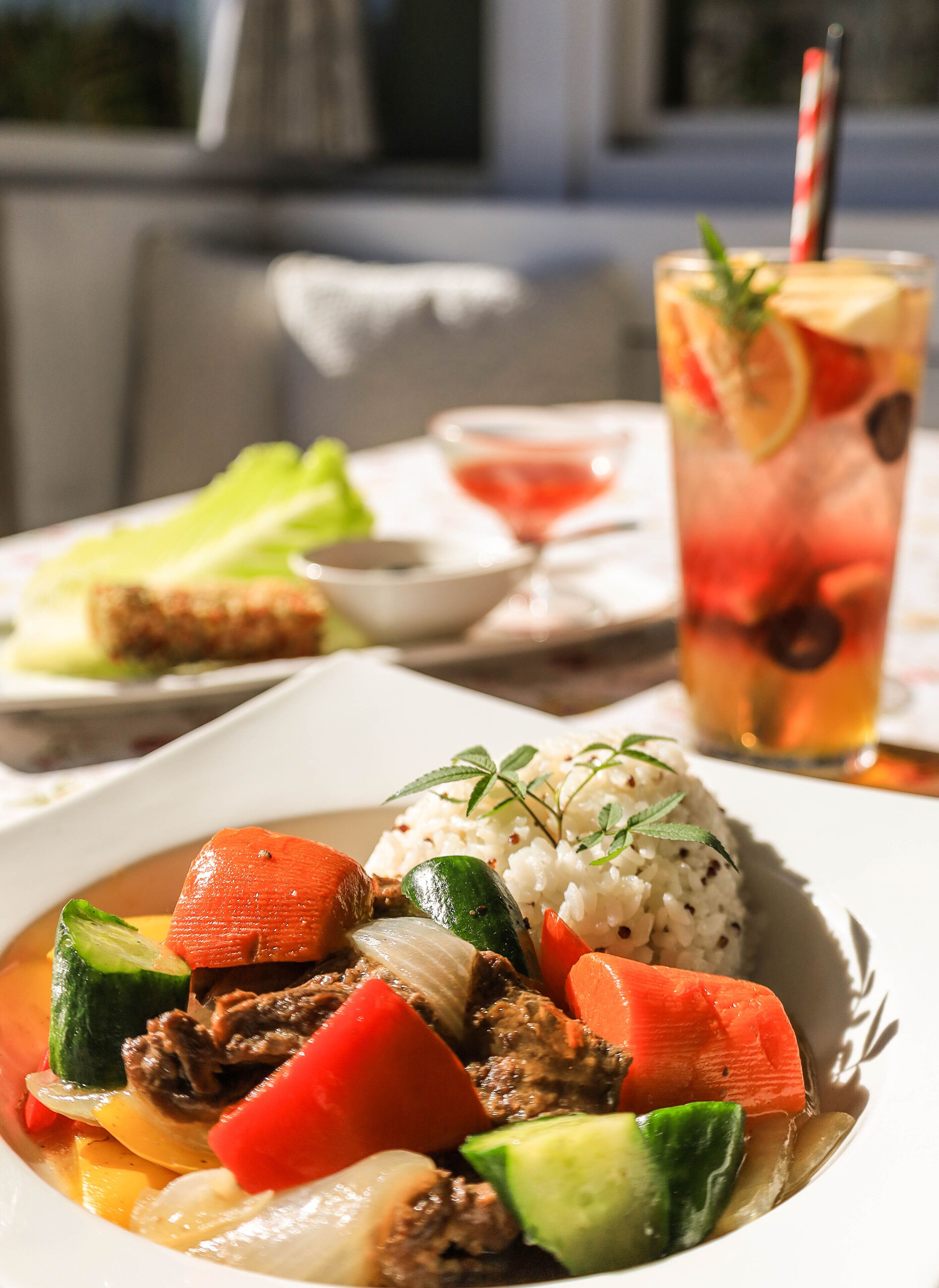 A meal with meat, vegetables, and rice, a drink with fruit and mint, and a dessert with a slice of cake.