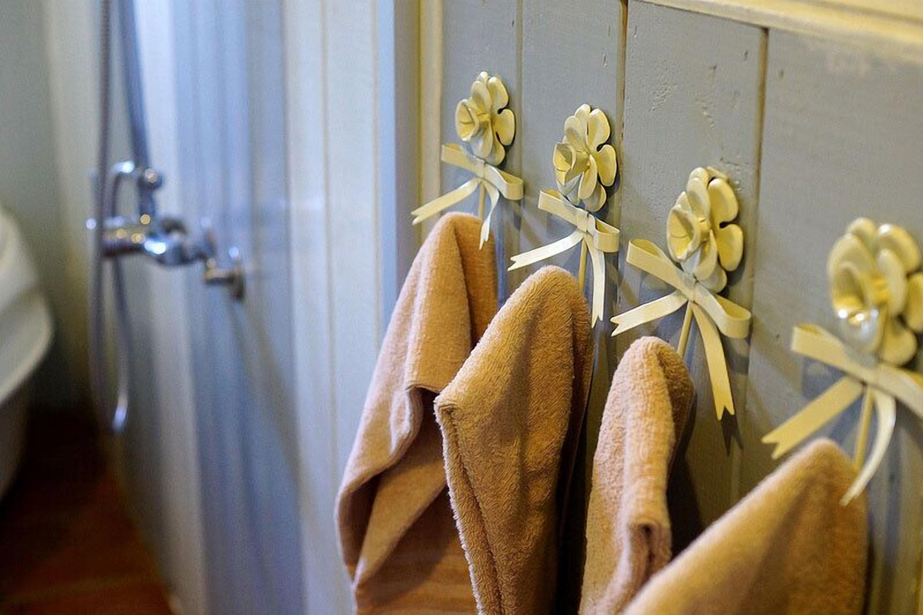 Un baño con toallas colgadas en un perchero y una ducha a la vista al fondo.