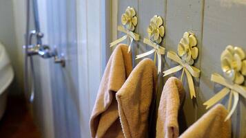 Un baño con toallas colgadas en un perchero y una ducha a la vista al fondo.