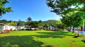 Ein Park mit Picknicktischen, einem Spielplatz und einem Gebäude mit roter Tür.