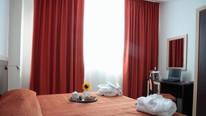 A hotel room with a bed, a desk with a laptop, a tray with breakfast items, and a window with red curtains. - Hotel Torre del Duca (San Floro)
