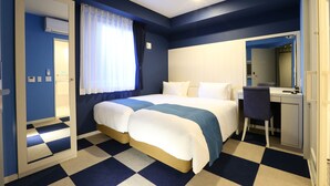 Ein Hotelzimmer mit Schachbrettmuster-Boden, einem Bett mit weißblauer Bettwäsche, einem Schreibtisch mit Stuhl und einem großen Spiegel.