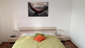 Et soveværelse med en seng, et natbord, en lampe og et billede af en ørn på væggen.
