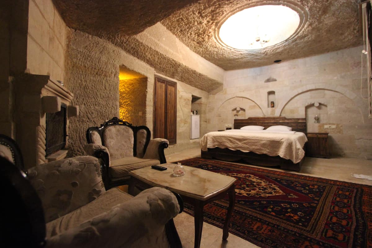 A traditional room with a bed, a chair, a table, and a carpet.