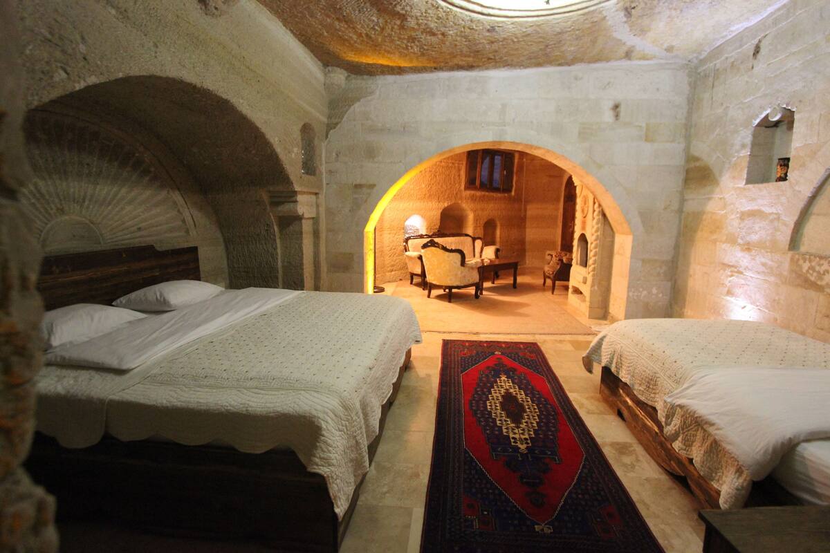 A room with two beds, a wooden floor, and stone walls.