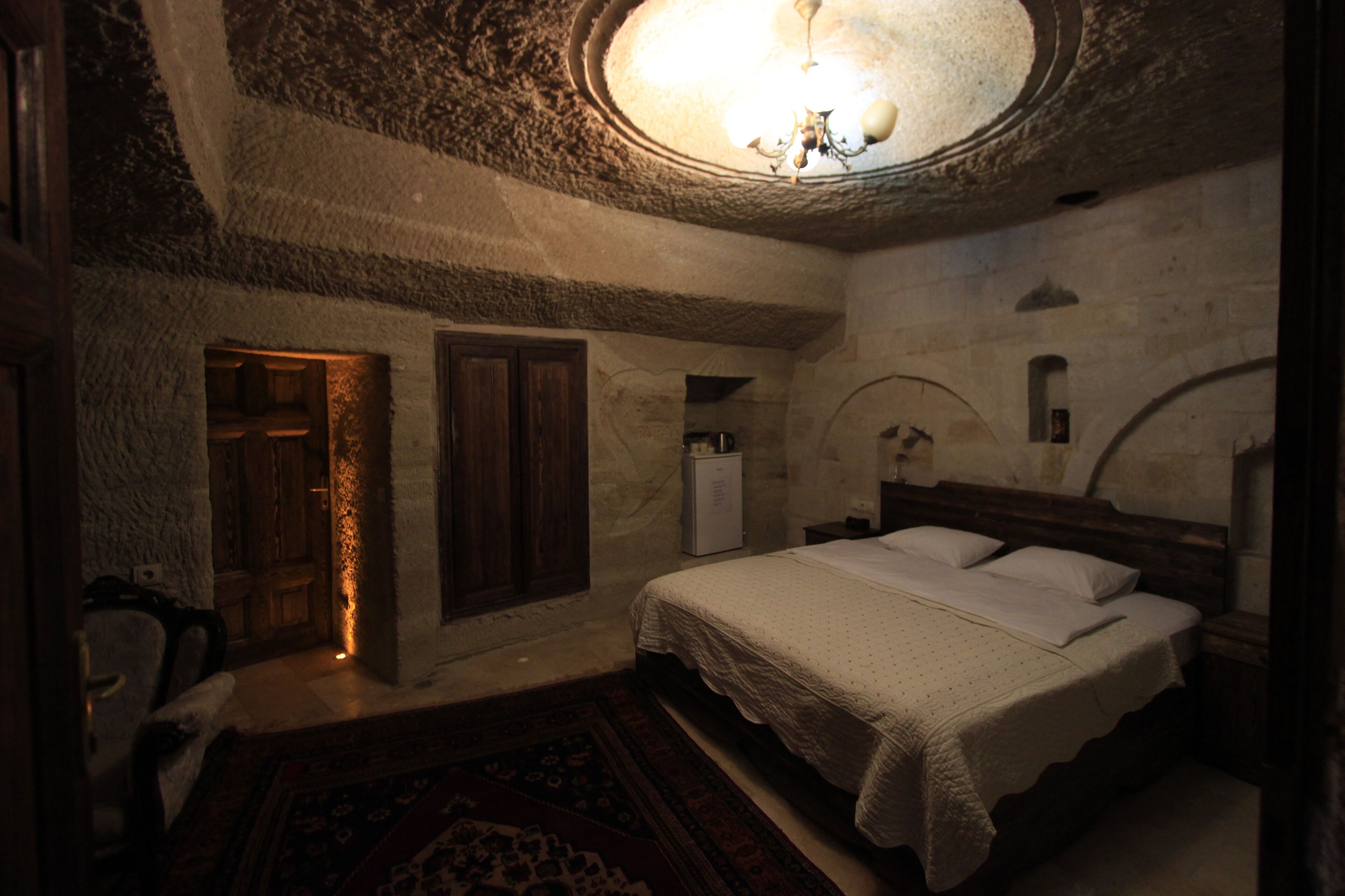 Een slaapkamer met een groot bed, een houten garderobe en een klein wit kastje.