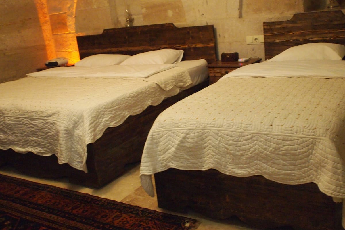 A room with two wooden beds, each with a white quilted bedspread.