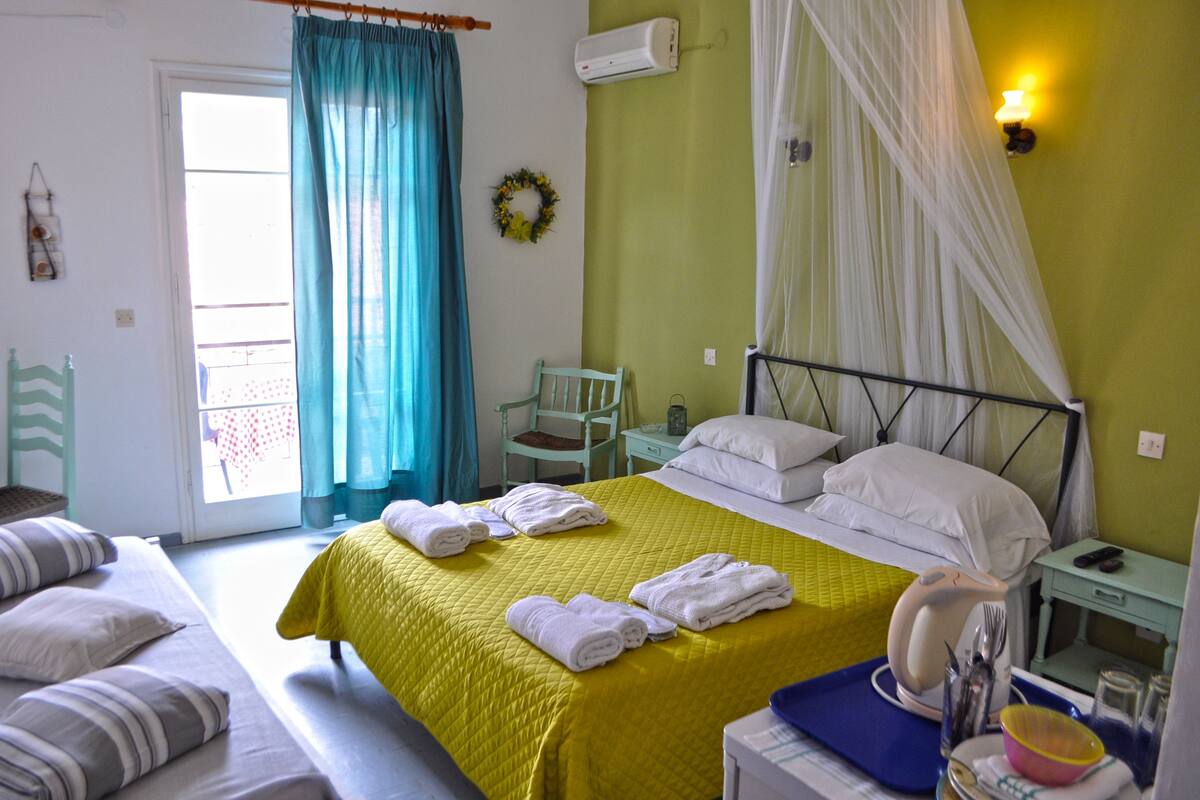 A hotel room with a bed, a chair, a nightstand, and a window with curtains.