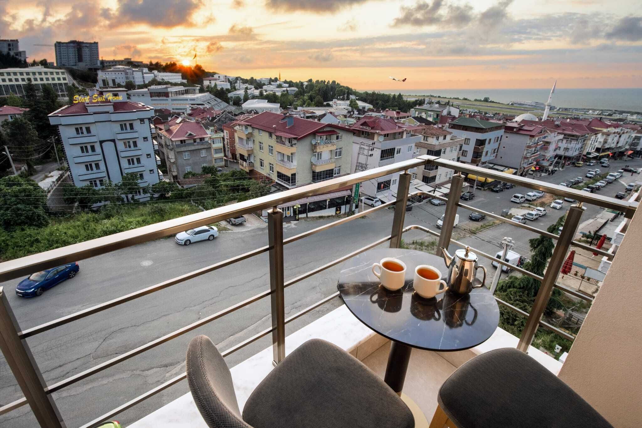 Ein Balkon mit Tisch und Stühlen, mit Blick auf eine Stadtlandschaft mit Gebäuden und einer Straße.