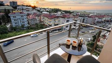 Ein Balkon mit Tisch und Stühlen, mit Blick auf eine Stadtlandschaft mit Gebäuden und einer Straße.