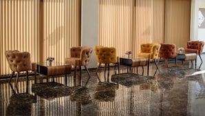 A seating area with plush armchairs and a glass coffee table, featuring a polished marble floor and vertical blinds. - White House Hotel (Trabzon)