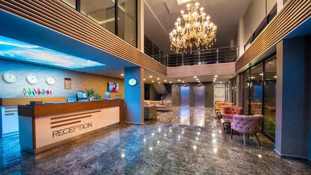 A modern reception area with a marble floor, a reception desk, a chandelier, and seating area. - White House Hotel (Trabzon)