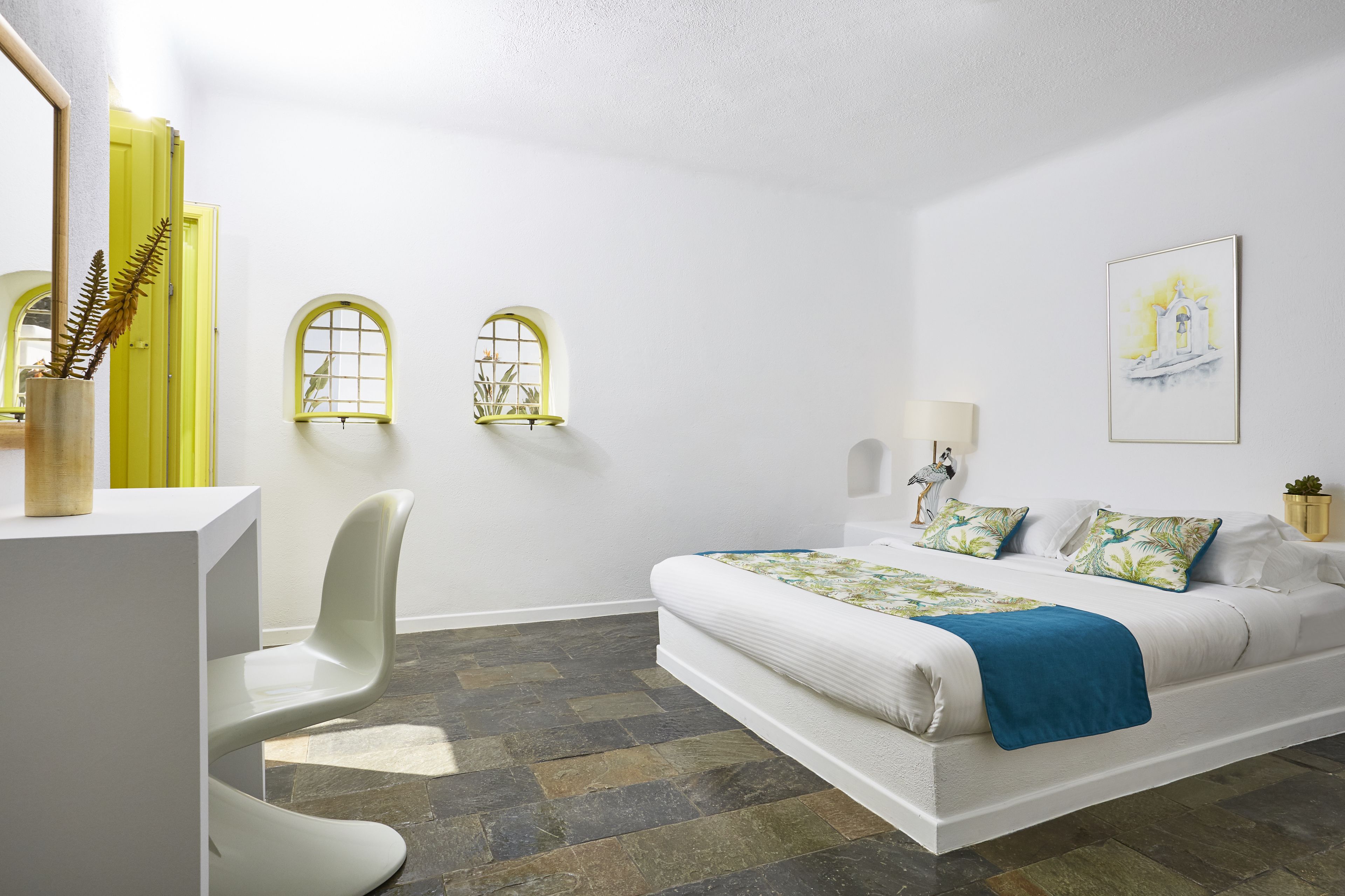 Un dormitorio moderno con una cama, un escritorio y dos ventanas de arco.