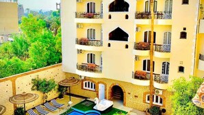 Um hotel com piscina, várias varandas e vegetação exuberante.