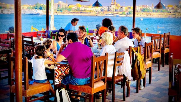 Um restaurante com mesas ao ar livre e vista para a orla marítima.