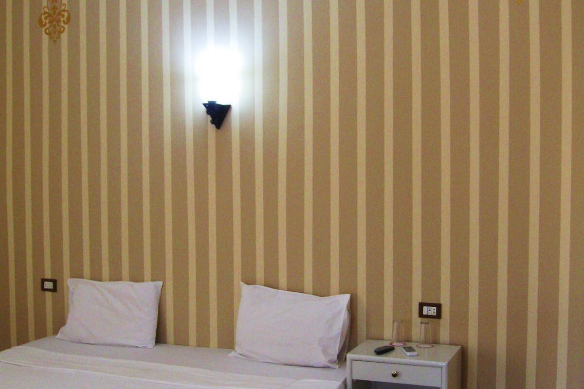 Ein Hotelzimmer mit einem Bett, Nachttischen und einem Sessel.