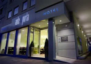 Ein Hotel Eingang mit Glasfassade, einem Schild mit der Aufschrift 'Hotel Arte Porte' und einem kleinen Weihnachtsbaum davor.