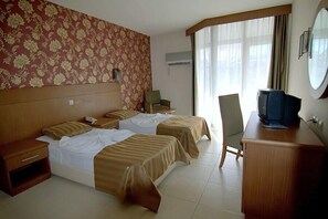 Habitación de hotel con dos camas, televisión, escritorio y una silla.