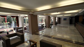 A spacious lobby with a marble floor, several seating areas, and large windows offering views of the outside. - Surtel Hotel (Kusadasi)