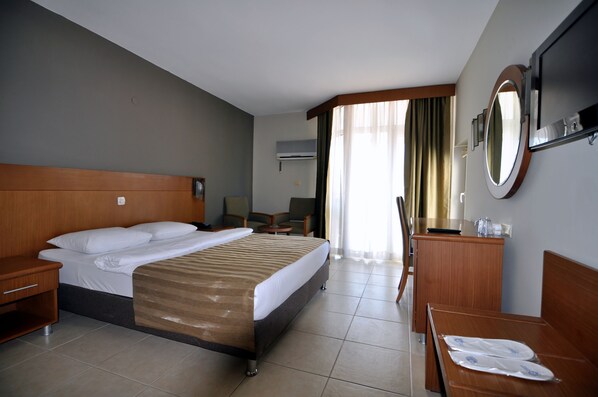 Una habitación de hotel con cama, mesita de noche, escritorio, silla y espejo.