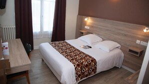 Una habitación de hotel con una cama, mesitas de noche, un escritorio y una ventana con cortinas.