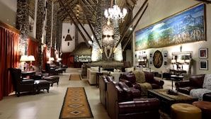 A spacious lobby with leather sofas, a stone wall, and a mural of elephants. - Lake Manyara Kilimamoja Lodge (Lake Manyara National Park)