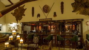 Een bar met een bord waarop 'Explorers' Bar' staat, een houten toog en stoelen met een zebraprint.