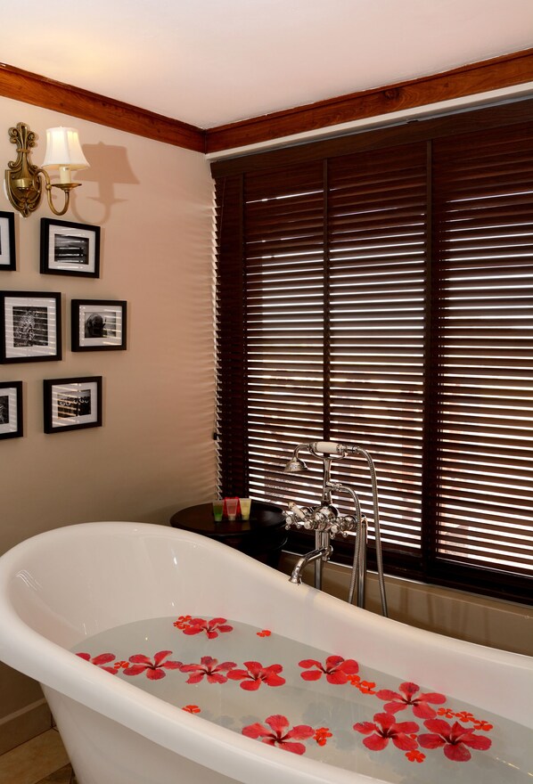 A bathroom with a freestanding bathtub filled with water and red flowers, wooden blinds, and framed pictures on the wall. - Ngorongoro Oldeani Mountain Lodge (Karatu)