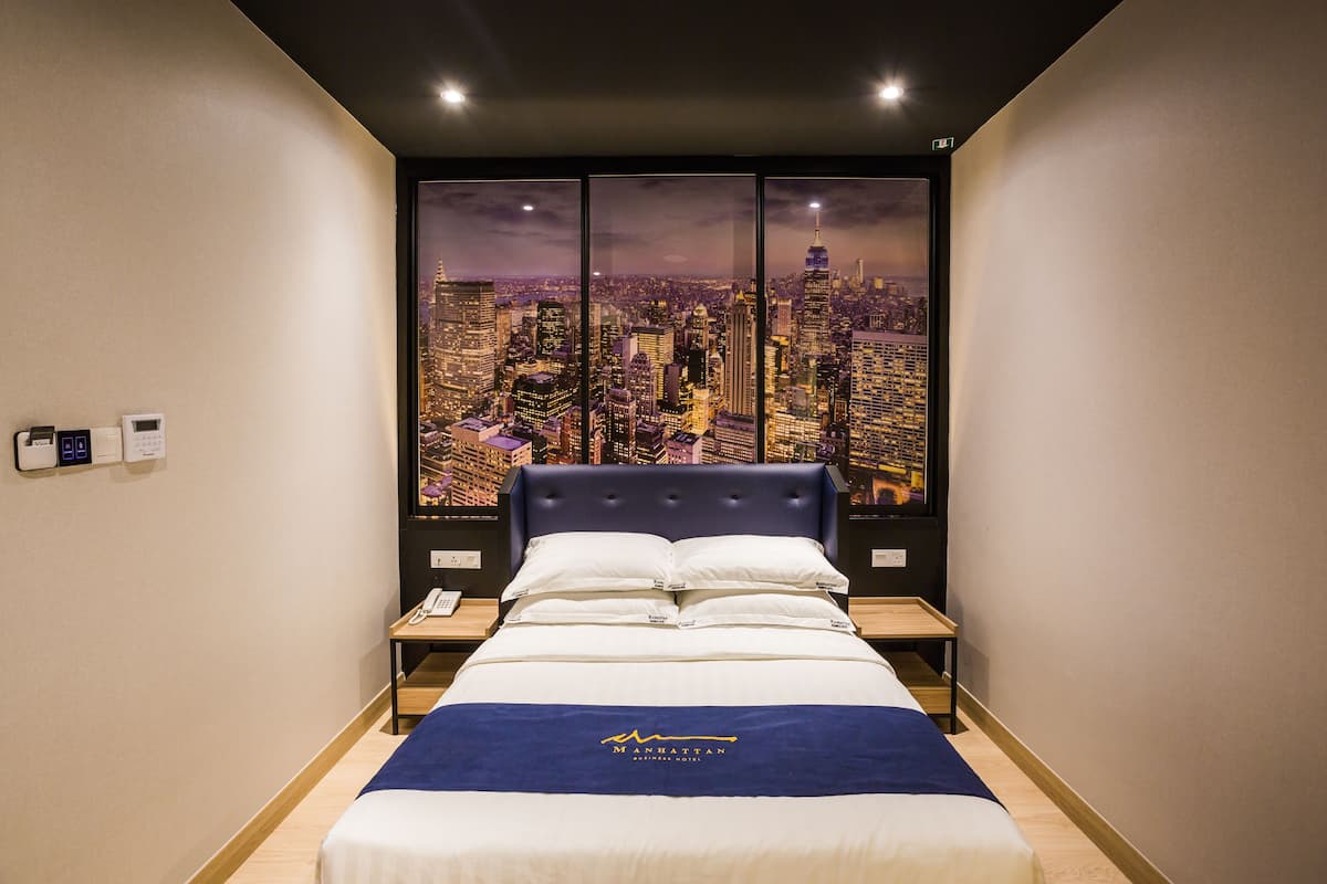 Une chambre d’hôtel avec un grand lit, une table de chevet, un téléphone et une vue sur la ville.