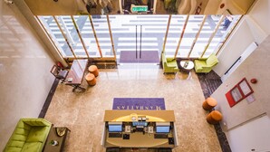 A lobby with a reception desk, two green sofas, a coffee table, and a large window with a view of the street. - Manhattan Business Hotel TTDI (Kuala Lumpur)