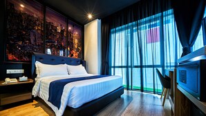 A modern hotel room with a large bed, a cityscape view, a desk with a chair, and a television. - Manhattan Business Hotel TTDI (Kuala Lumpur)