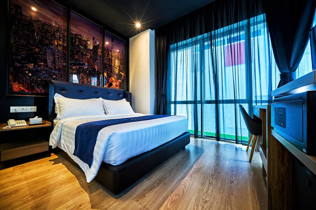 Une chambre d’hôtel moderne dotée d’un grand lit, offrant une vue sur la ville, d’un bureau avec une chaise et d’une télévision.