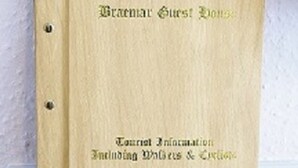 A wooden guest book with embossed text reading "Guest Book" and "Tourist Information Including Whales & Dolphins."