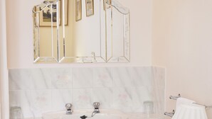 A bathroom with a white sink, a mirror with a decorative frame, and a towel rack.