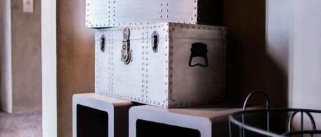A stack of vintage-style suitcases with metal latches, placed on top of white storage boxes.