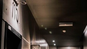 A corridor with doors marked with numbers, a wall-mounted light fixture, and a door with a sign above it. - M Boutique Kampar (Kampar)
