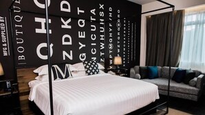 A modern hotel room with a large bed, a sofa, and a wall with large letters. - M Boutique Kampar (Kampar)