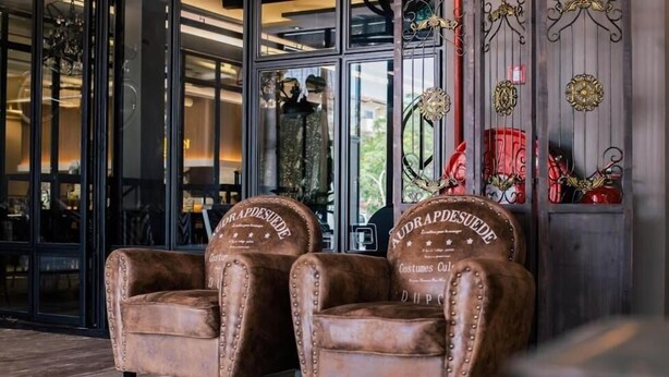Two leather armchairs with embossed text, positioned in front of a glass door leading to a room with a view. - M Boutique Kampar (Kampar)