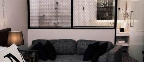 Ein Hotelzimmer mit einem großen Bett, einem Schlafsofa, einem Nachttisch und einem Fenster mit Jalousien.