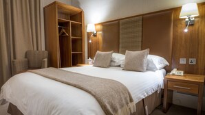 A hotel room with a large bed, a wooden wardrobe, a bedside table with a lamp, and a telephone. - Mackays Hotel Wick (Wick)