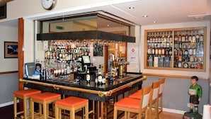 A bar area with a counter, stools, and a variety of bottles and glasses. - Mackays Hotel Wick (Wick)